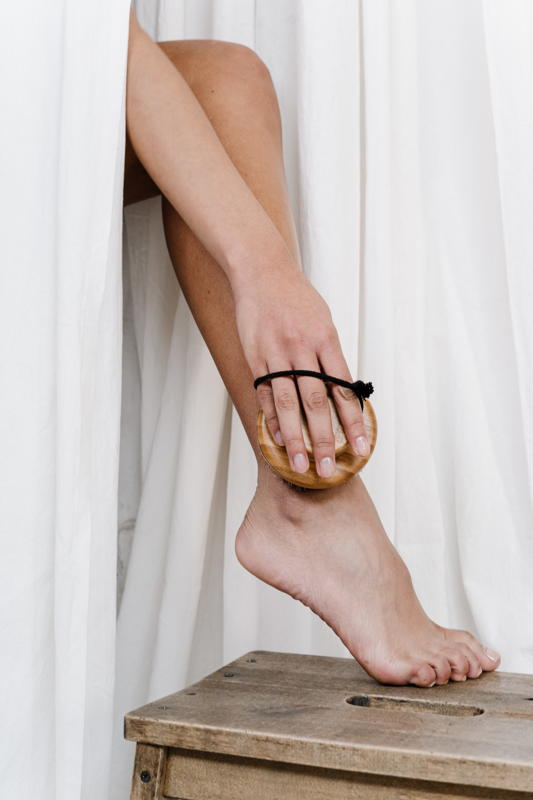 donna fa scrub sulla gamba con una spazzola di crine